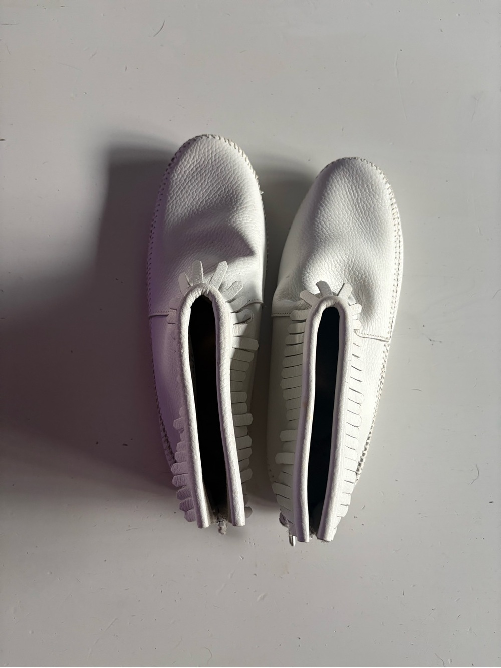 White leather Minnetonka soft-sole moccasins.